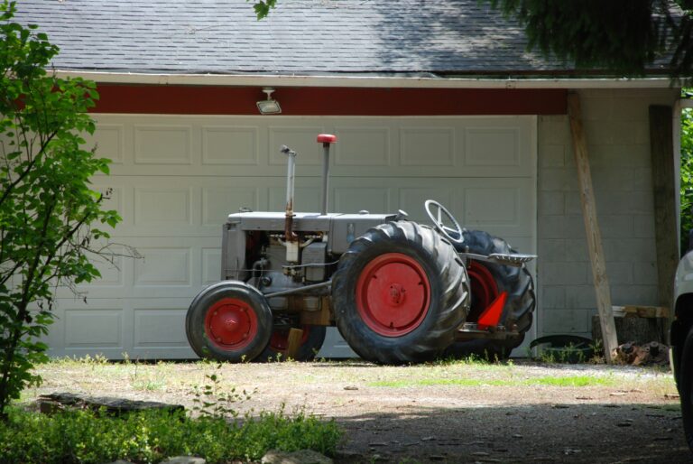 red tractor parked beside white wooden house during daytime