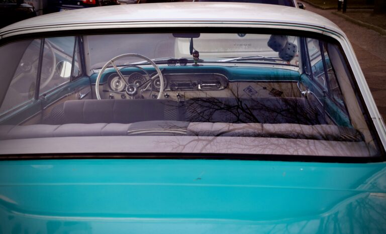 The rear interior of a vintage turquoise car.