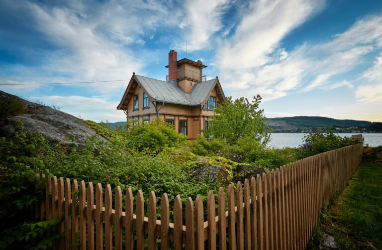 brown wooden house surrounded by fence near body of water