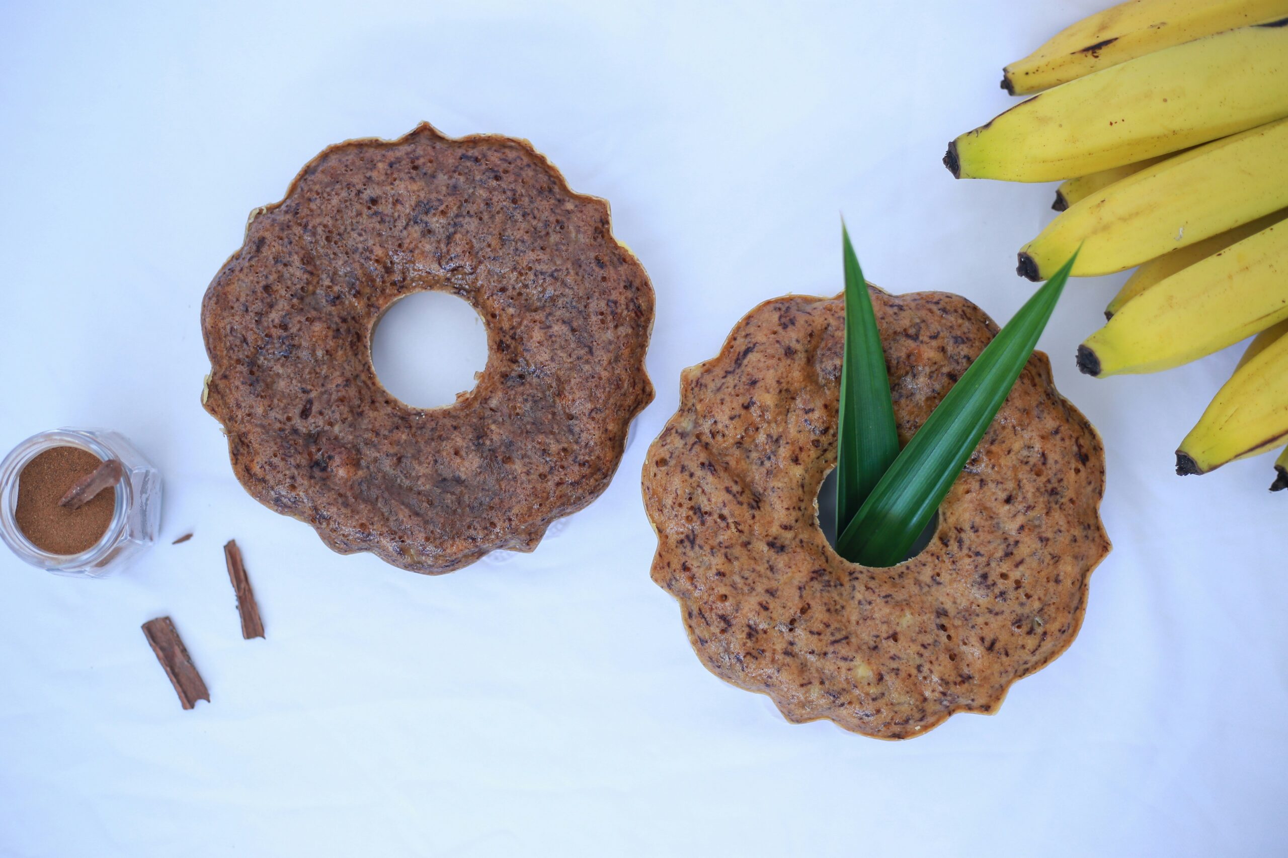 A table topped with two donuts and bananas